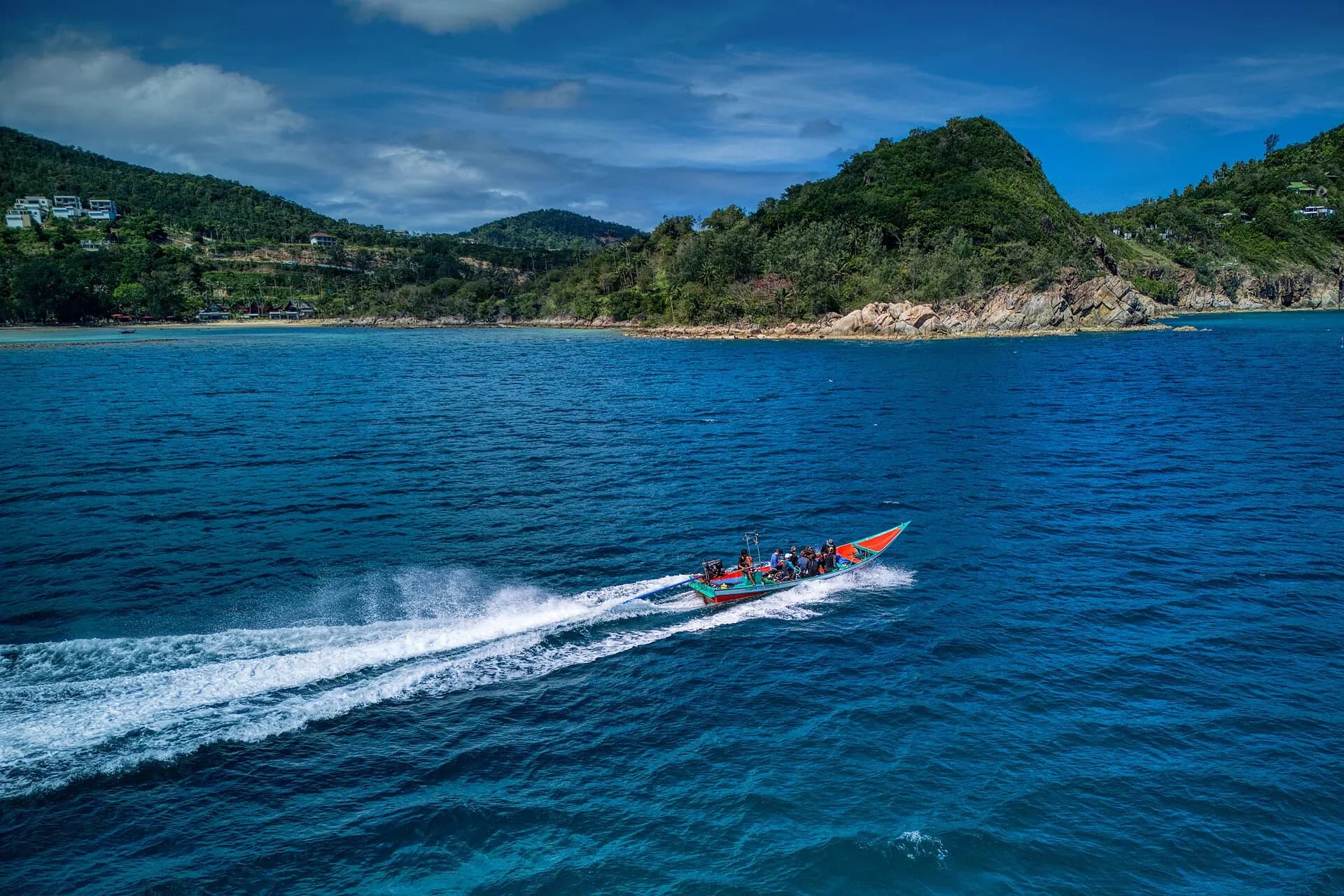 A speedboat carving a white wake through deep blue water off the north coast