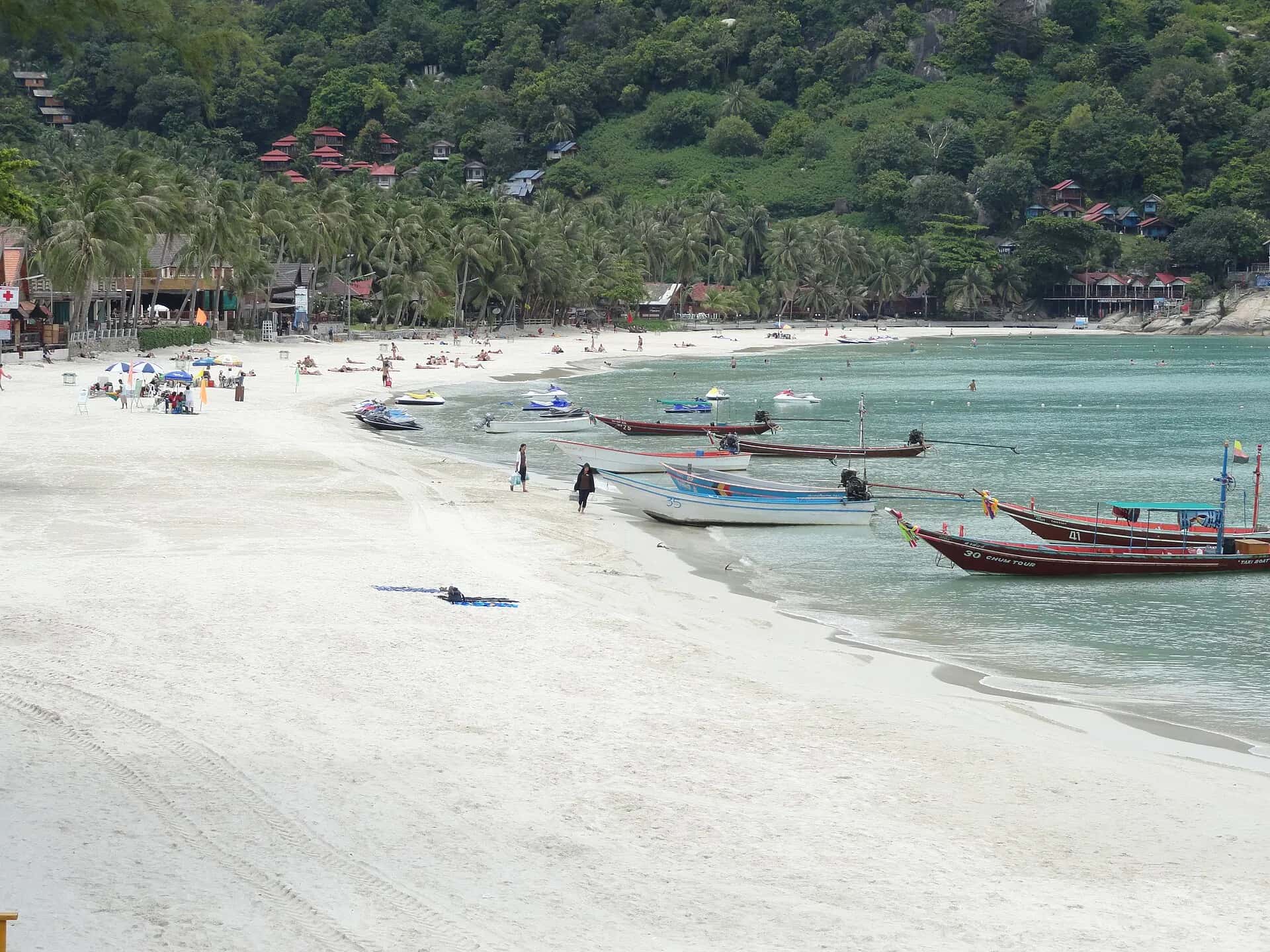 Longtail boats lined up on the white sand of Haad Rin's Sunrise Beach