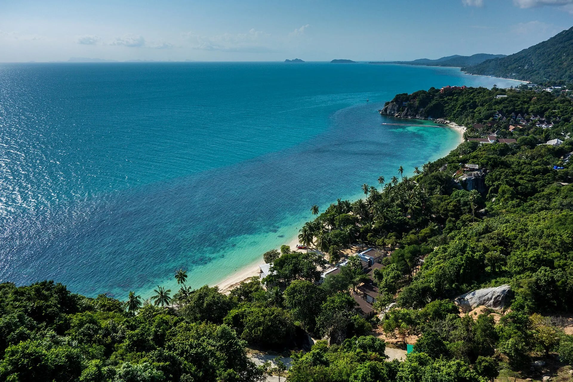 Turquoise water along a palm-fringed bay on Koh Phangan, seen from a hilltop